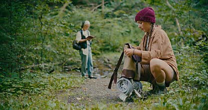 Woman Packing Backpack While Crouching Near Plants