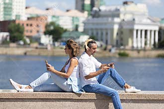 Modern addictions - a man and a woman sit buried in smartphones during a date.