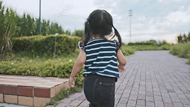 Young Asian Caucasian mixed race girl enjoy running in the park, rear view. Happy kid childhood life. Healthy child concept