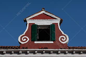 View of an atique window in an Italian house in Burano, Italy against a clear blue sky background
