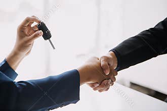 A car rental company employee is handing out the car keys to the renter after discussing the rental details and conditions