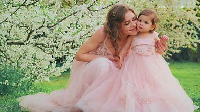 Little cute girl daughter kisses young mom woman on cheek. Smiling face positive emotional Portrait happy family. Spring