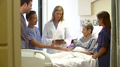 Medical Team Talking To Senior Female Patient In Hospital