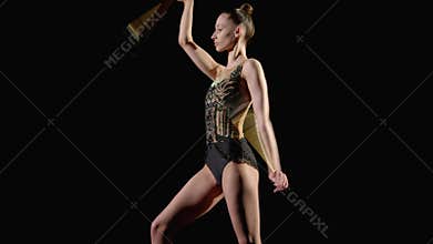Side view of elegant rhythmic gymnast practicing rotation elements with clubs