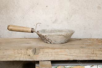 Rusty Metal Scoop on Wooden Surface with Concrete Dust