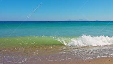 Waves crashes on Kos island beach in Aegean Sea with stereo sound and distant Mediterranean mountains.