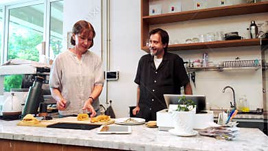 Small business owners prepare fresh pastries and collaborate at their cozy cafe counter. The image reflects teamwork,