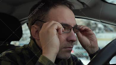 a driver with poor eyesight puts on glasses. Young man have problems with driving due poor eyesight, hand holding