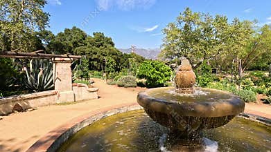 footage of a water fountain with lush green trees and plants and colorful flowers at Descanso Gardens