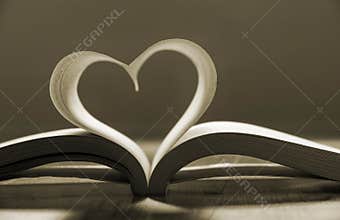 Open book with pages forming heart shape .