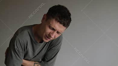 Young man suffering from stomach pain. Male holding belly with painful expression. Concept of digestive problem
