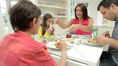 Hispanic Family Sitting At Table Eating Meal Together