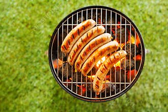 Beef bratwurst grilling over a barbecue fire