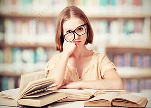 Tired funny girl student with glasses reading books