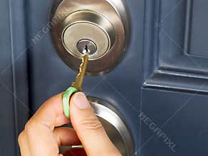 Female hand putting house key into door lock