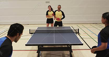 Playing table tennis, mixed doubles team in yellow uniforms competing indoors
