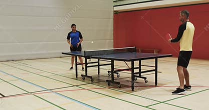 Playing table tennis, man and woman competing in indoor sports hall