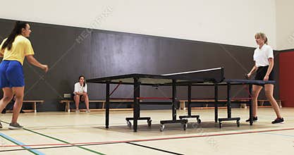 Playing table tennis, two women competing in indoor sports facility
