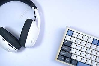 White keyboard with blue and dark keycaps, and headphones, top-down view, suggesting a digital workspace setup.