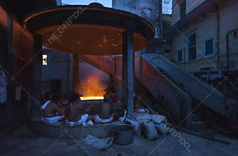 Hindu people sit around fire at night