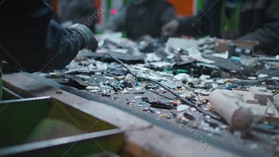 Sorting garbage on a conveyor belt. Male workers inspect a pile of garbage at a recycling facility