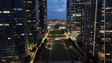 Real-time aerial video of sunset in Singapore skyline. Flight over the wall of skyscrapers in night lights