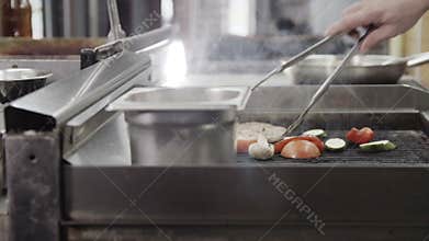 Professional chef cooking meat and vegetables on a