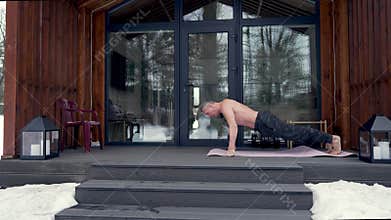A man does push-ups on the terrace of a house.