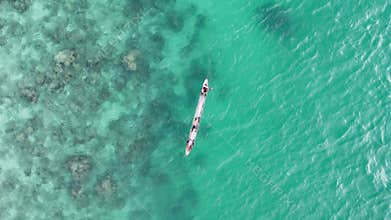 Overhead tracking drone shot of two fishermen paddling a canoe over th
