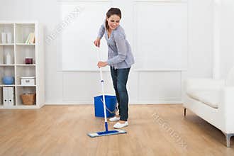 Woman cleaning hardwood floor of living room