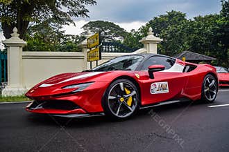 Red Ferrari SF90 stradale Plug-in Hybrid Electric Vehicle PHEV hypercar driving on the wet road after rain