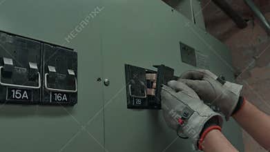 Electrician\'s Gloved Hand Turning On Circuit Breaker in Electrical Panel