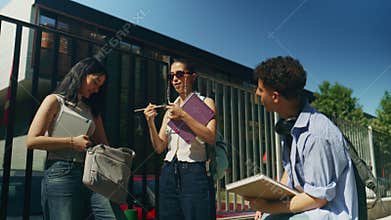 Happy High School Students Discussing and Sharing Items Outdoors on Campus