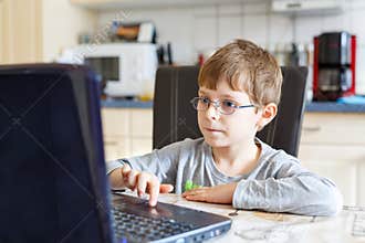 Kid boy with glasses surfing internet and playing on computer
