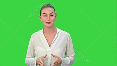 Portrait of a young business woman presenting something by a hand on a Green Screen, Chroma Key.