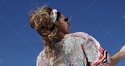 A strong wind blows on the beauty model in a stylish dress and sunglasses on a yacht.
