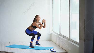 Squat. Lovely young woman doing squat in the fitness studio. Scene in the gym.