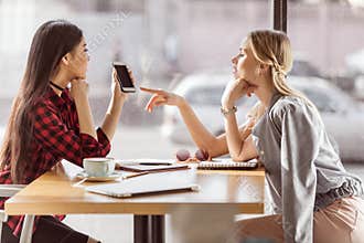 Young women talking while having business lunch meeting in cafe