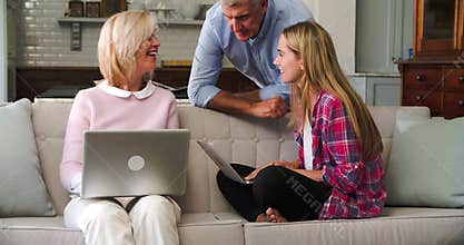Parents With Adult Daughter Using Laptop Computers At Home
