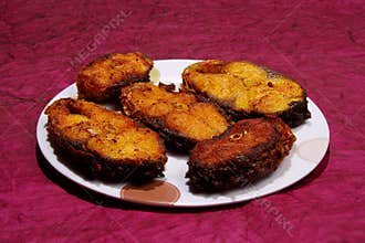 Slices of Rohu fish fry over maroon paper