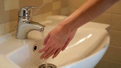 Turns on the water and begins to wash her hands under the water