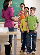 Students listen to teacher with clipboard