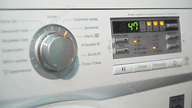 Woman chooses program cycle on a washing machine