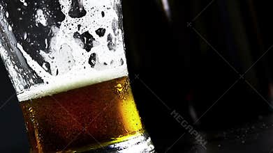 Man drink fresh beer with foam in front of beer bottles background