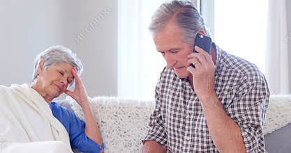 Focused elderly couple calling doctor