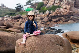 Bored child holding fish net for outdoors activity on vacation