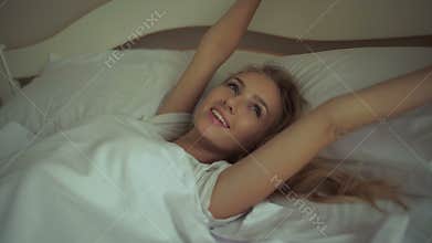 Fresh and happy woman in bed wakes up in the morning smiling