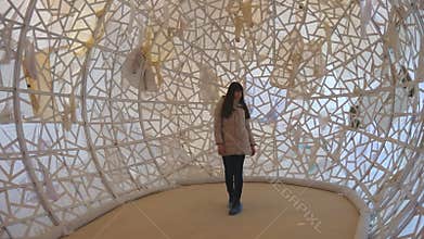 Young woman walking inside of contemporary art object at museum. Girl examining modern art