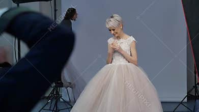 Young female model poses and smiles during photoshoot. Action time. Blond model poses and smiles