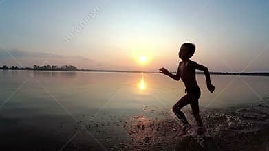 Happy Child Runs Along the Beach at Sunset. Slow Motion